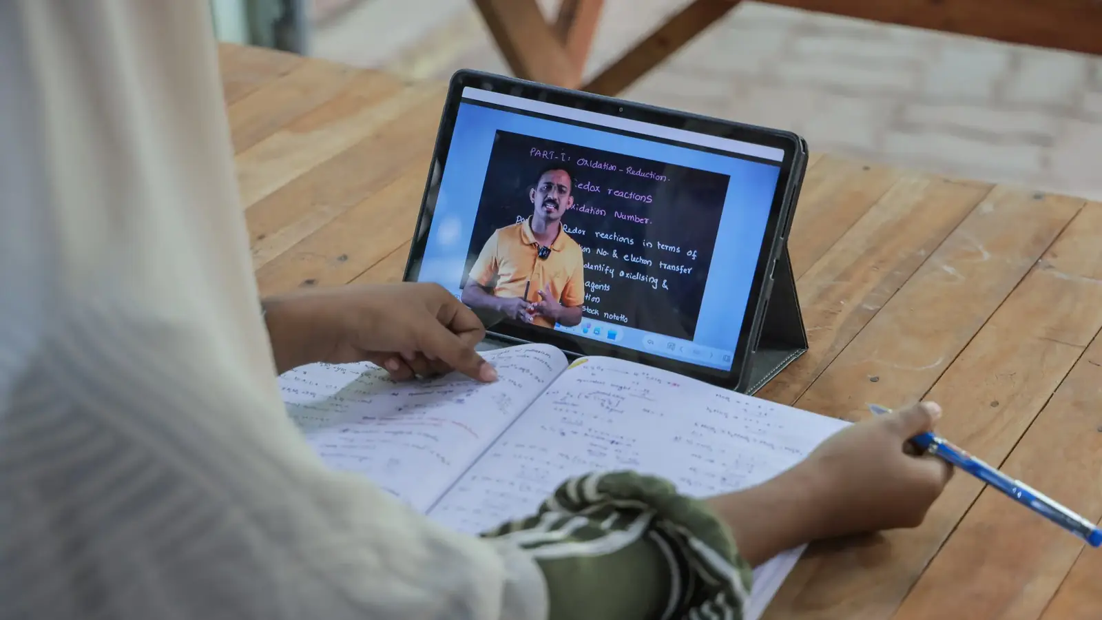 A student watching a recorded lecture on a tablet